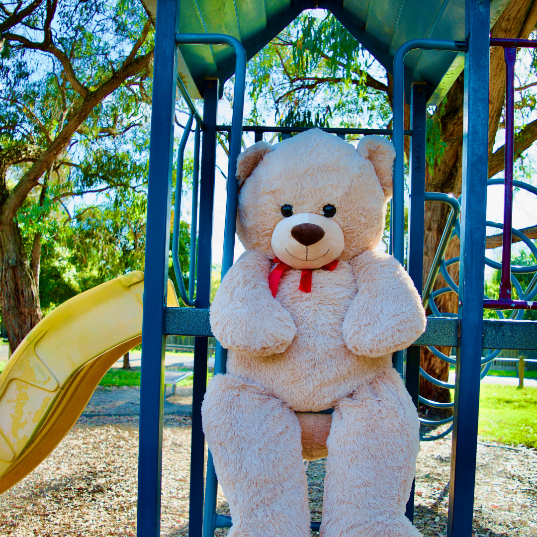 a giant teddy bear plush is sitting on the stairs in the park