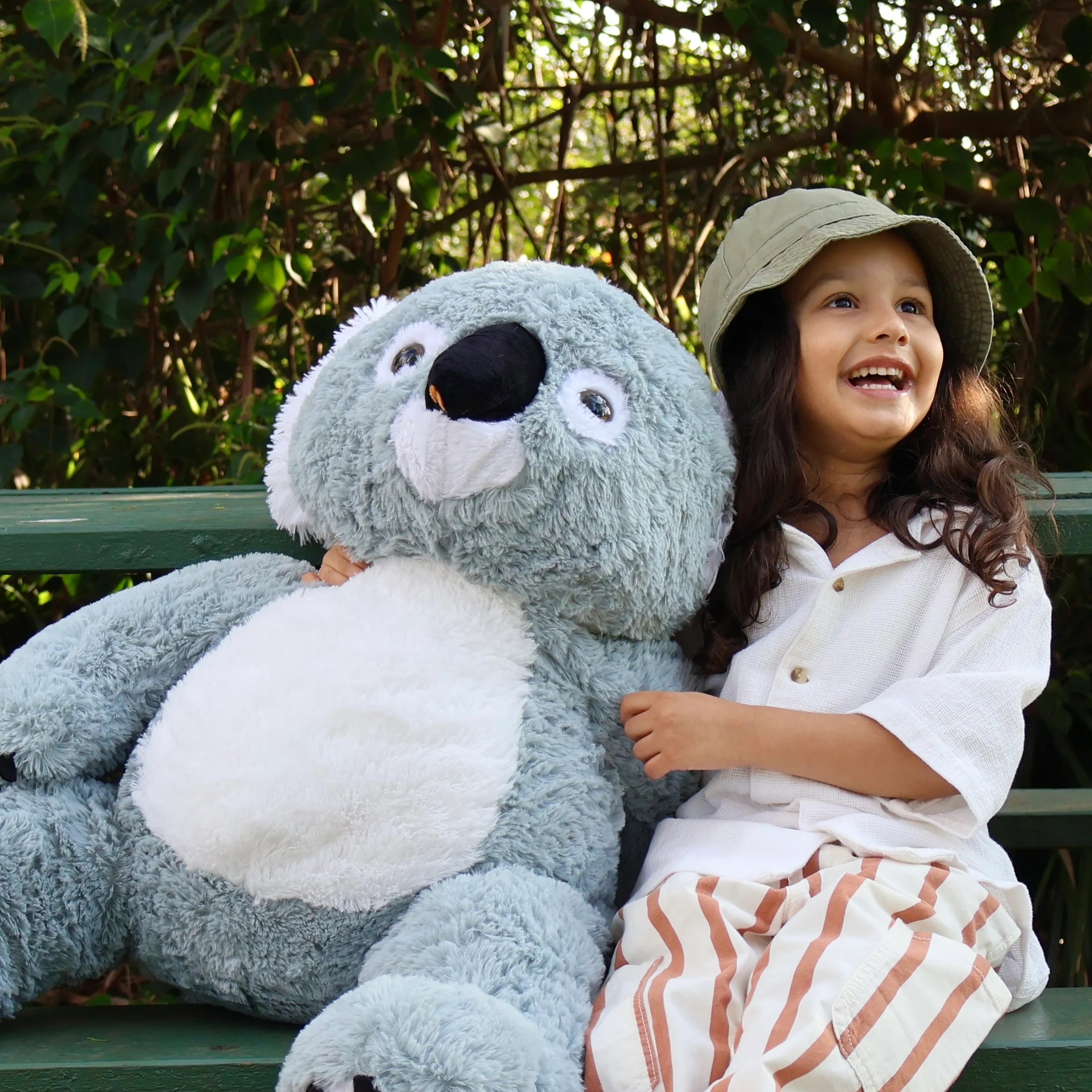 A kid is hugging Glassie, a giant koala plush toy.