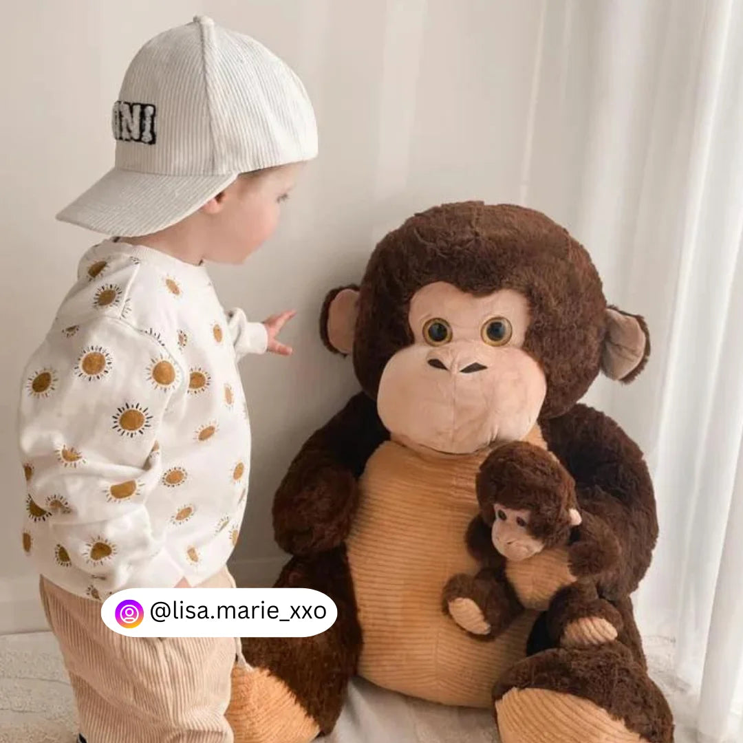 A child sitting next to an 80cm giant monkey plush named Cookies and Cream from Dreamzity, looking excited.