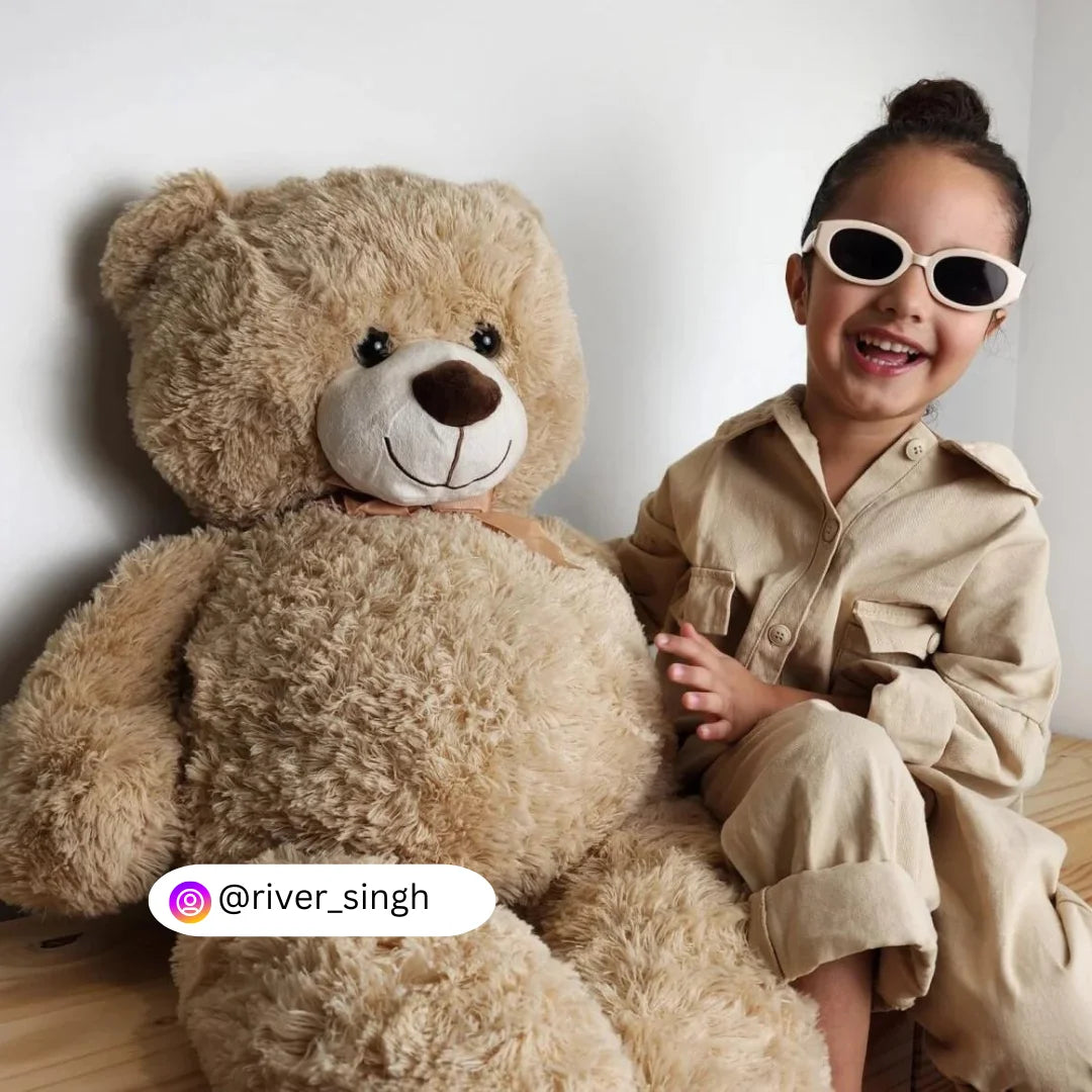 A child sitting next to a 100cm giant teddy bear plush named Goldchi from Dreamzity, showcasing the plushie's large and huggable design.